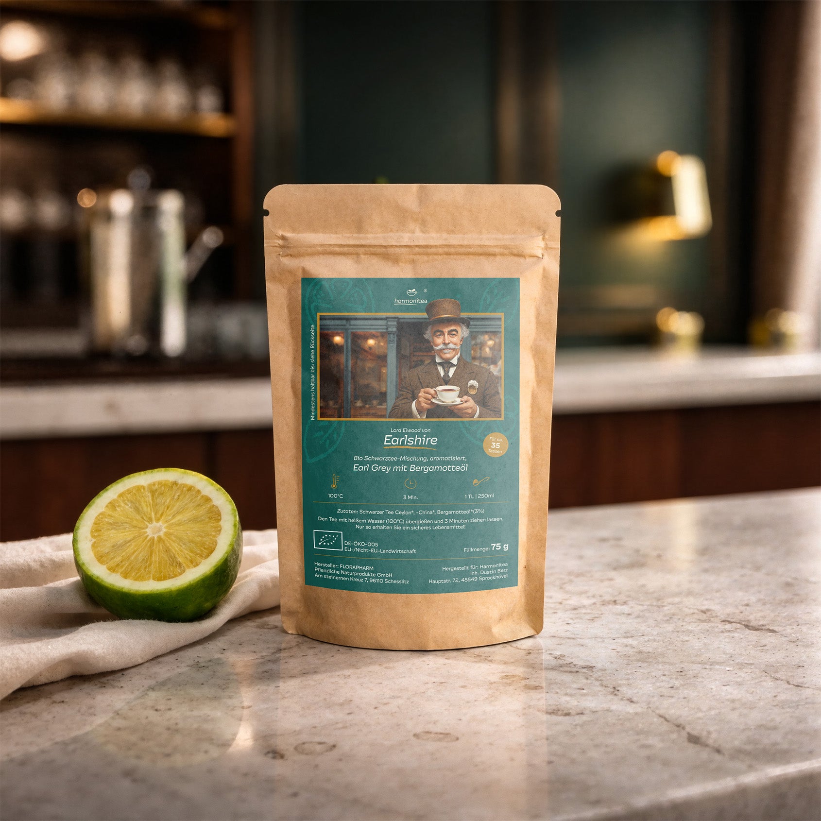 Nachhaltige Kraftpapier-Verpackung von Lord Elwood Bio Earl Grey Schwarztee mit Bergamotteöl auf einer Marmor-Küchenzeile neben einer frischen Bergamotte-Frucht.